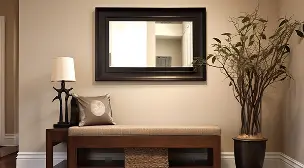 Entryway bench with pillow, lamp on side table, large mirror above, and tall plant in a pot.